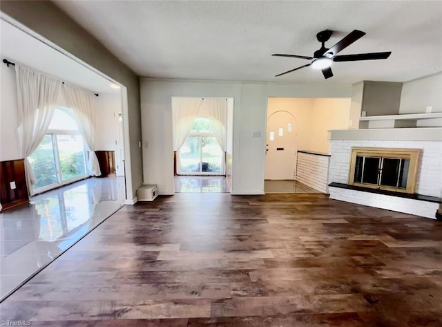 unfurnished living room with ceiling fan, a fireplace, and dark hardwood / wood-style floors