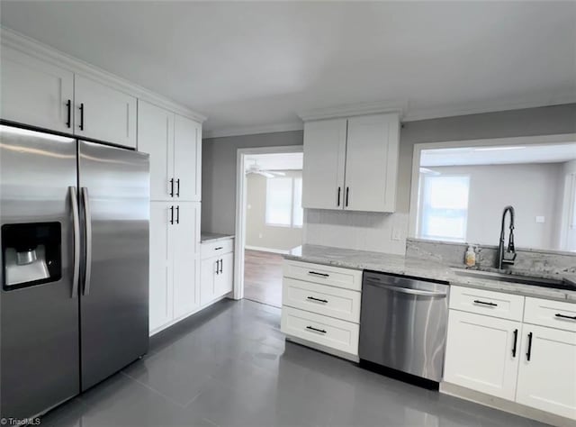 kitchen featuring white cabinets, light stone counters, appliances with stainless steel finishes, and sink