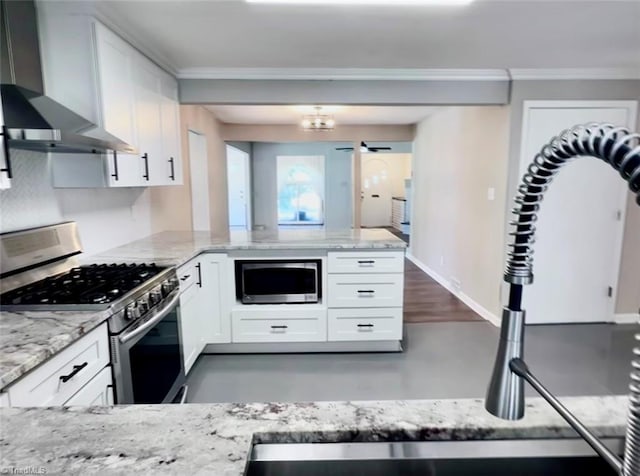 kitchen featuring white cabinets, ornamental molding, wall chimney range hood, appliances with stainless steel finishes, and light stone countertops