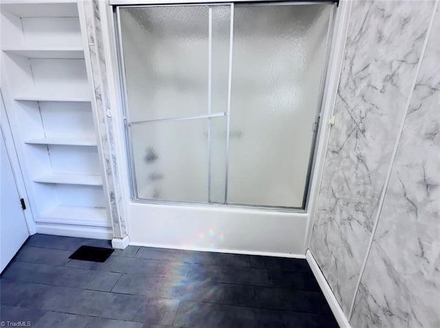 bathroom featuring combined bath / shower with glass door