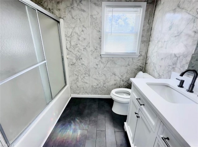 full bathroom with enclosed tub / shower combo, vanity, hardwood / wood-style floors, and toilet