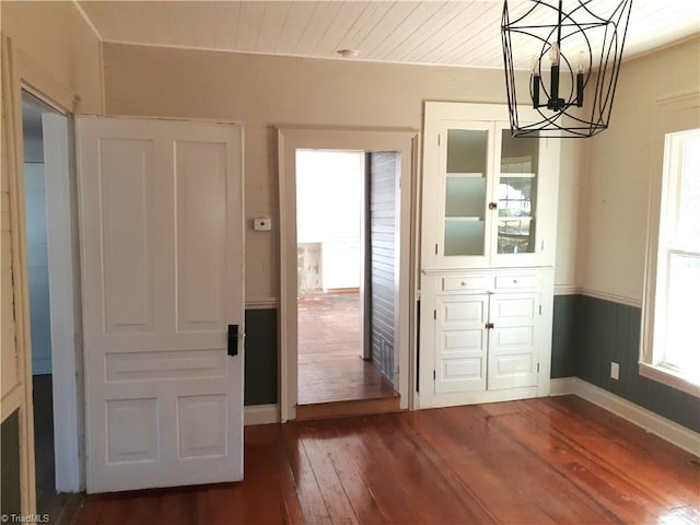 unfurnished dining area with dark hardwood / wood-style flooring and a notable chandelier