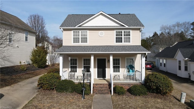 traditional home featuring covered porch and roof with shingles