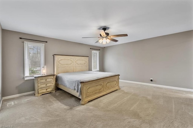 bedroom with light carpet, ceiling fan, visible vents, and baseboards