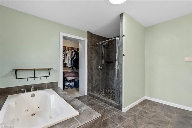 full bathroom with a jetted tub, a shower stall, baseboards, and a spacious closet