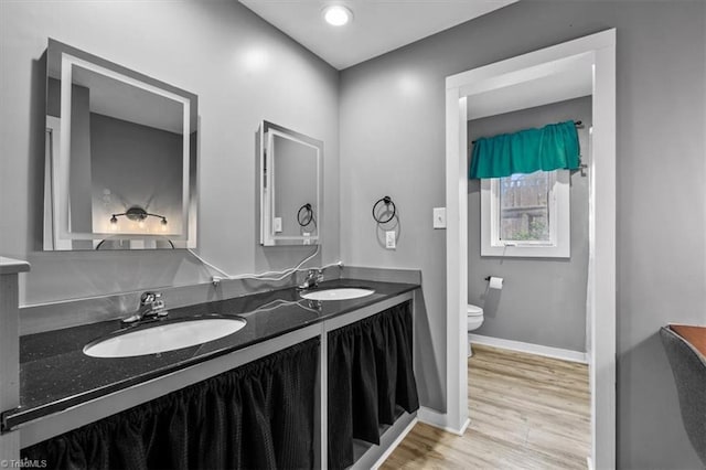 full bath featuring toilet, baseboards, a sink, and wood finished floors