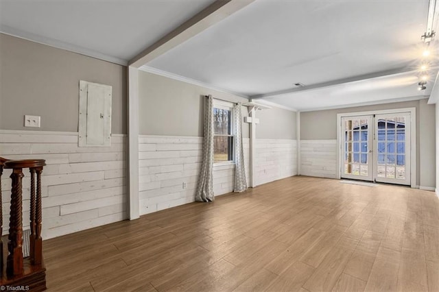 empty room featuring french doors, wainscoting, wood finished floors, and beam ceiling