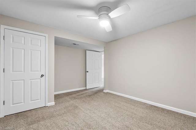 empty room with a ceiling fan, carpet flooring, visible vents, and baseboards