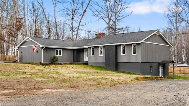 ranch-style house with a shingled roof, a chimney, and fence