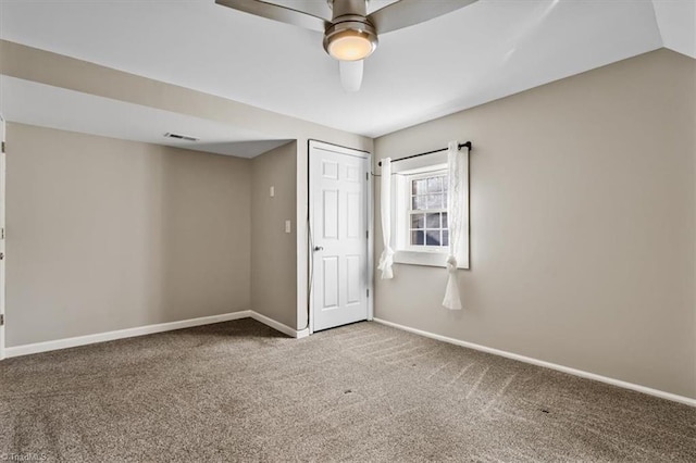 carpeted empty room with a ceiling fan, visible vents, vaulted ceiling, and baseboards