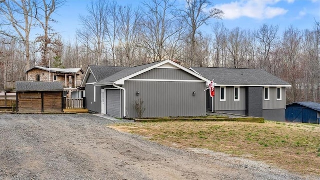 single story home with an attached garage, an outdoor structure, and gravel driveway