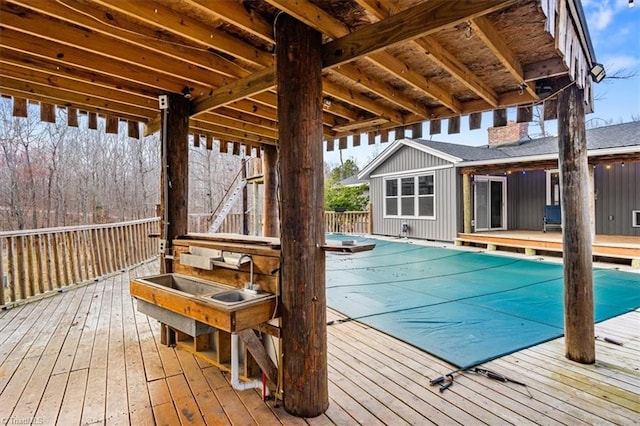 exterior space with a covered pool, a sink, and a wooden deck