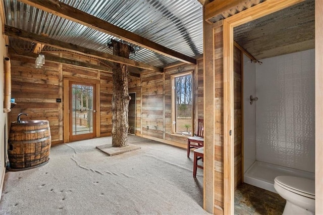 interior space with carpet, plenty of natural light, wooden walls, and decorative columns