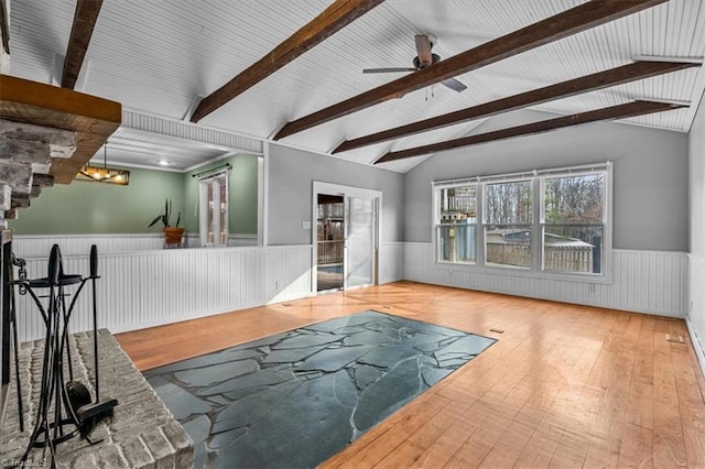 living area featuring lofted ceiling with beams, ceiling fan with notable chandelier, wainscoting, and wood-type flooring