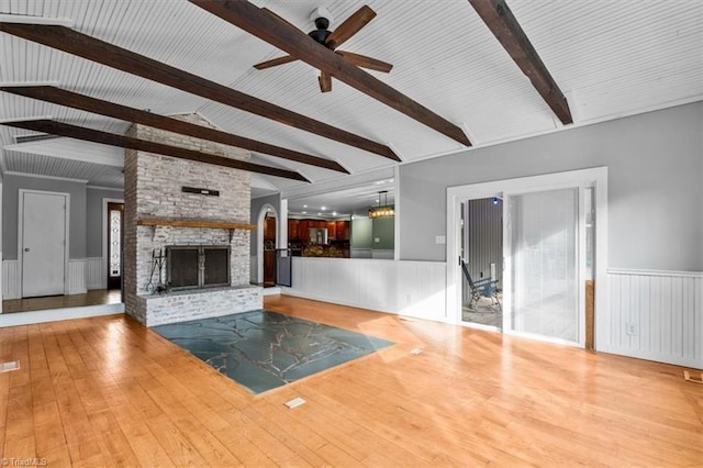 unfurnished living room featuring a large fireplace, wainscoting, and wood-type flooring