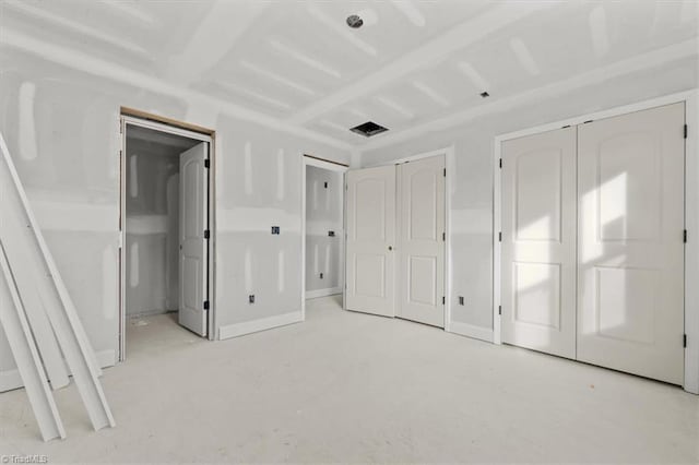 unfurnished bedroom with visible vents, concrete floors, baseboards, and two closets