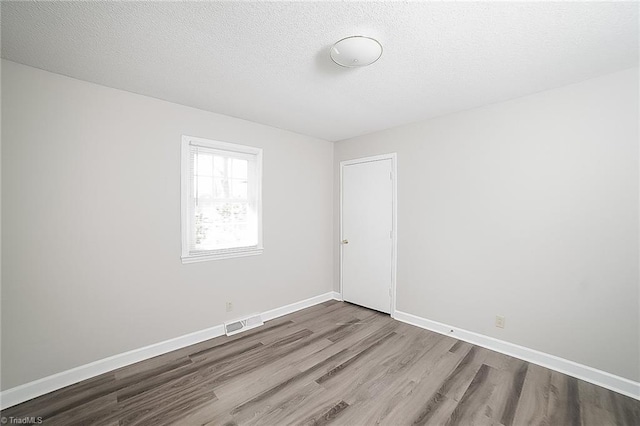 unfurnished room with hardwood / wood-style floors and a textured ceiling