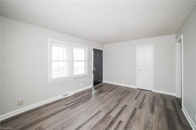 unfurnished room with wood-type flooring and a textured ceiling