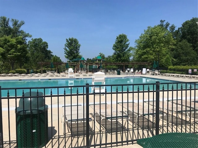community pool featuring a patio area, fence, and cooling unit