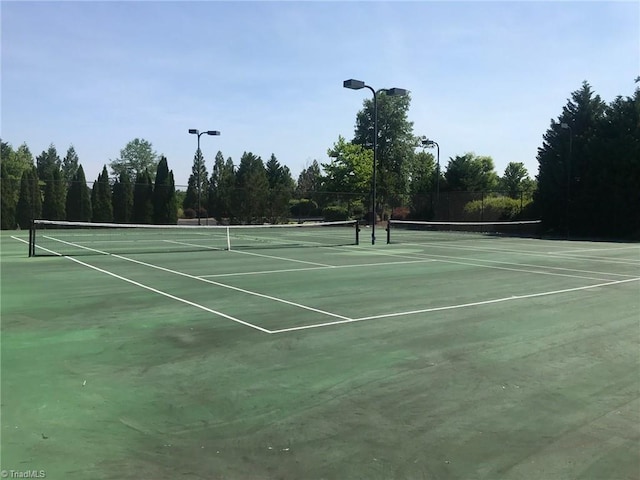 view of tennis court with community basketball court and fence