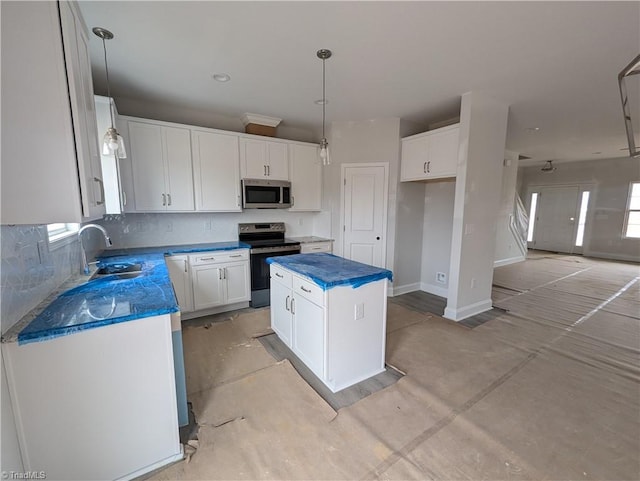 kitchen with stainless steel appliances, a sink, a center island, white cabinets, and decorative backsplash