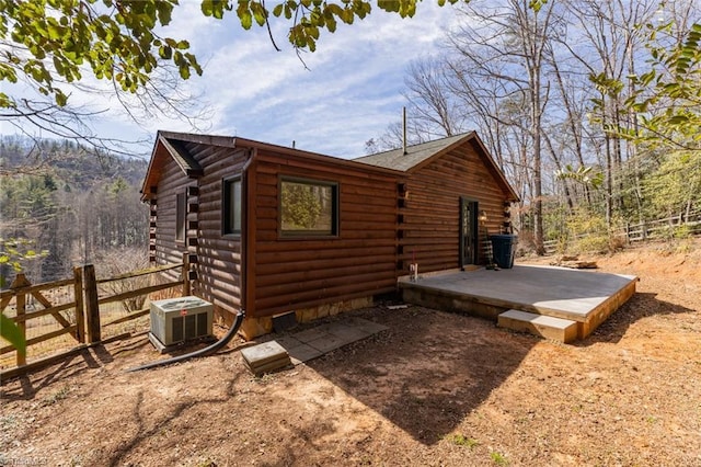 view of side of property with a patio area, central AC, fence, and log siding