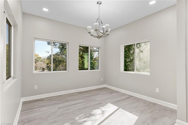 empty room with an inviting chandelier and light hardwood / wood-style flooring