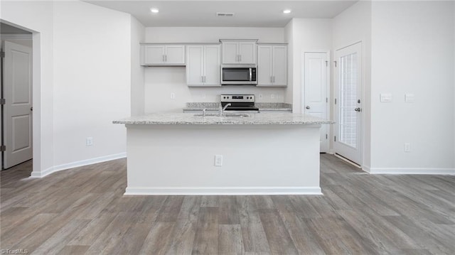 1914 Frost Dr, Haw River, NC 27258 - kitchen featuring appliances with stainless steel finishes, a sink, a kitchen island with sink, baseboards, and light wood-style flooring