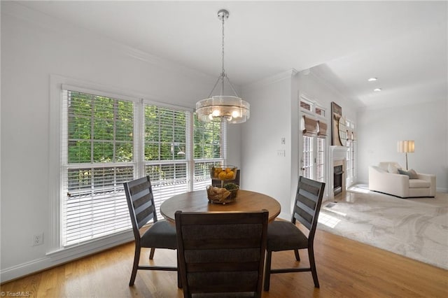 dining room featuring a chandelier, crown molding, baseboards, a fireplace, and wood finished floors