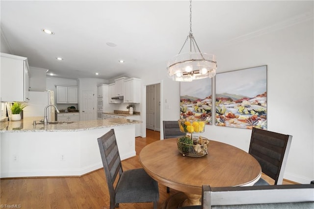 dining space featuring crown molding, light wood-style floors, recessed lighting, and a chandelier