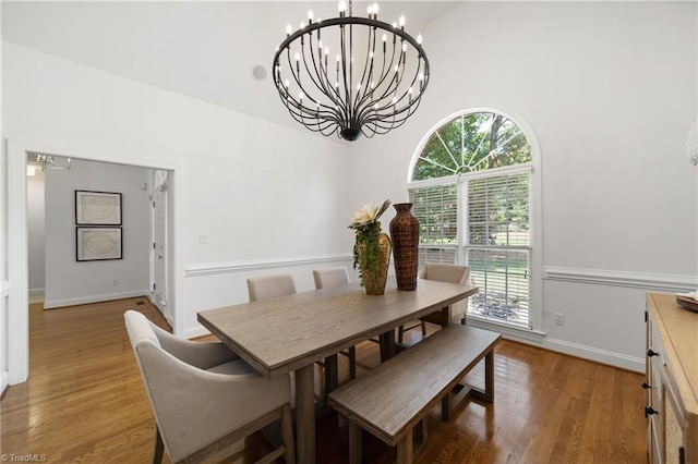 dining space with a chandelier, plenty of natural light, wood finished floors, and a high ceiling