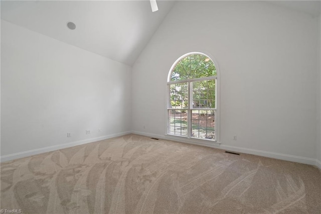 carpeted empty room with baseboards and high vaulted ceiling