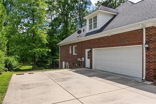 view of property exterior featuring brick siding, roof with shingles, and concrete driveway