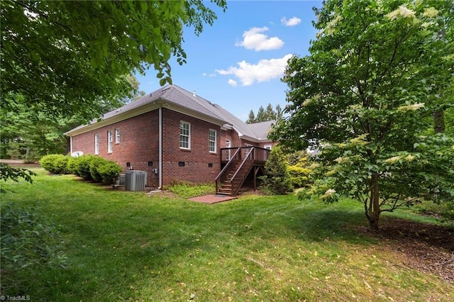 back of property with stairs, brick siding, central air condition unit, crawl space, and a lawn