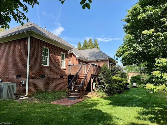 rear view of property with cooling unit, brick siding, stairs, and a lawn