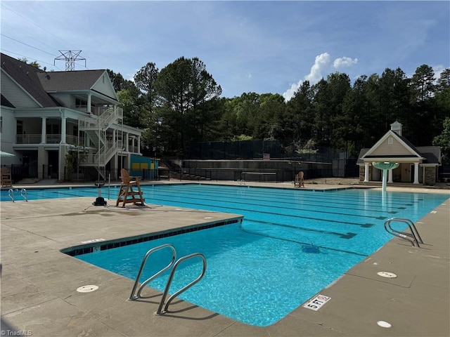 community pool with fence, a patio area, and stairs