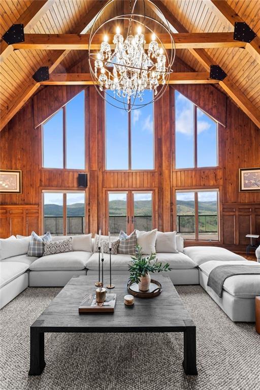 living room featuring wooden ceiling, high vaulted ceiling, wood walls, and a notable chandelier