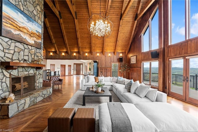 living room with beam ceiling, a stone fireplace, high vaulted ceiling, and wooden ceiling