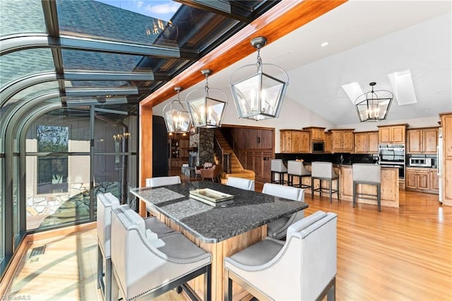 interior space featuring vaulted ceiling with skylight, an inviting chandelier, and light hardwood / wood-style floors