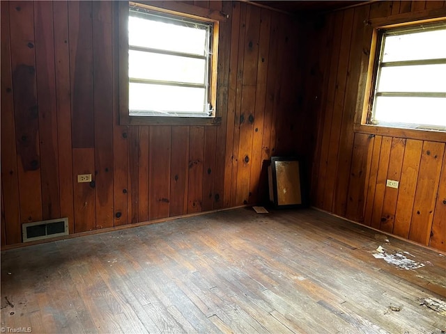 empty room featuring wood walls and hardwood / wood-style floors