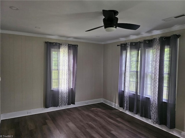 empty room featuring a healthy amount of sunlight, crown molding, dark wood-type flooring, and ceiling fan