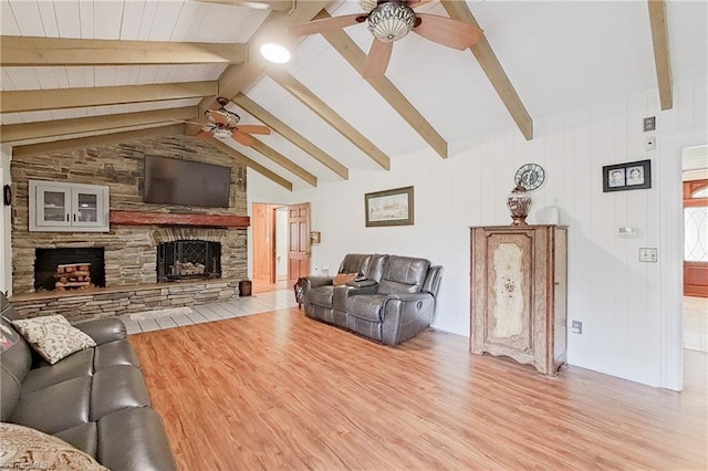 living room with vaulted ceiling with beams, a stone fireplace, ceiling fan, and light wood-type flooring