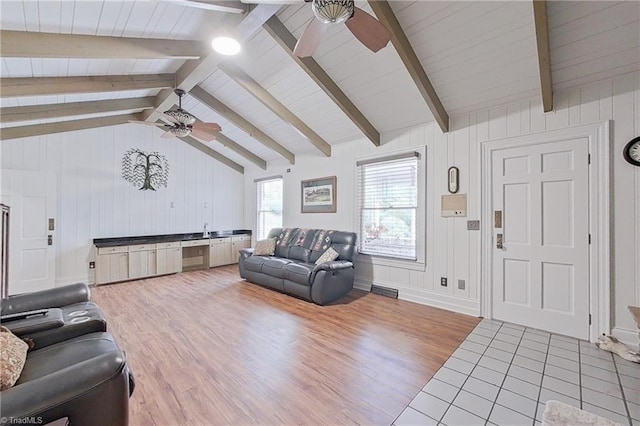 tiled living room featuring ceiling fan and vaulted ceiling with beams