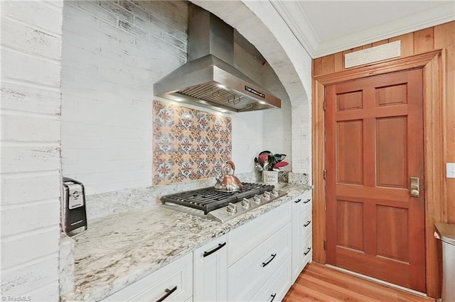 kitchen with light stone counters, extractor fan, white cabinetry, light hardwood / wood-style flooring, and stainless steel gas stovetop