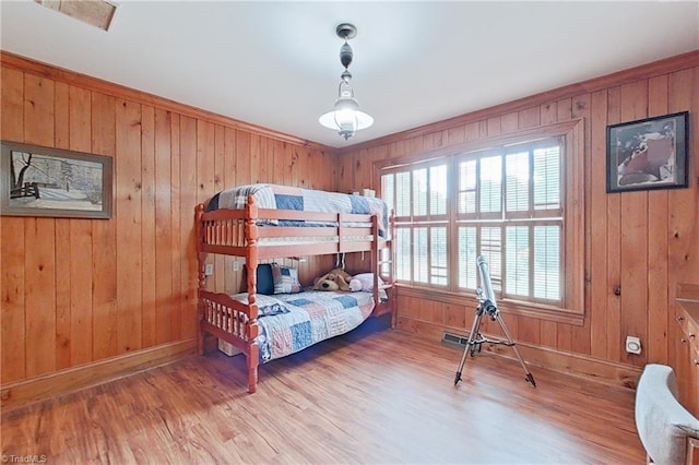 bedroom with light wood-type flooring and wood walls