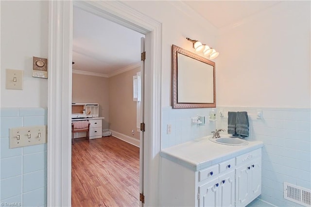 bathroom featuring tile walls, ornamental molding, large vanity, and hardwood / wood-style flooring