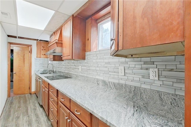 kitchen featuring light stone counters, tasteful backsplash, black electric stovetop, light hardwood / wood-style flooring, and sink