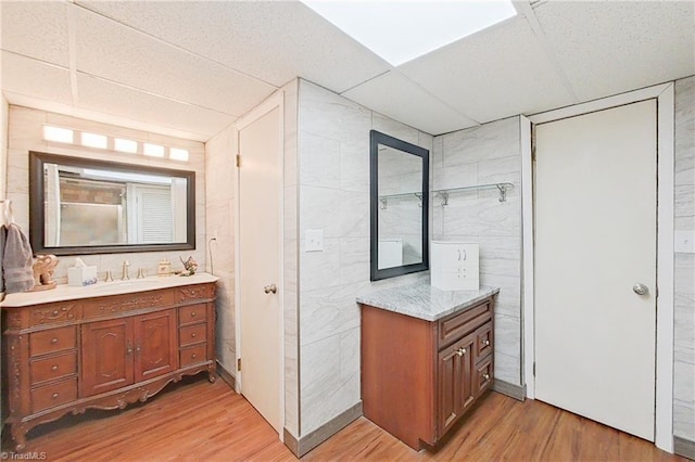 bathroom featuring tile walls, oversized vanity, hardwood / wood-style floors, and a paneled ceiling