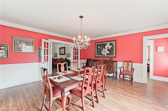 dining space with light hardwood / wood-style floors, a notable chandelier, and crown molding