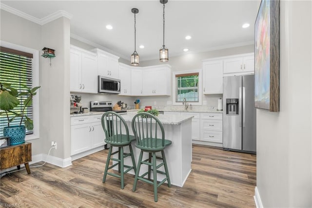 385 Apache Dr, Winston-Salem, NC 27107 - kitchen featuring appliances with stainless steel finishes, crown molding, white cabinetry, wood finished floors, and a kitchen island